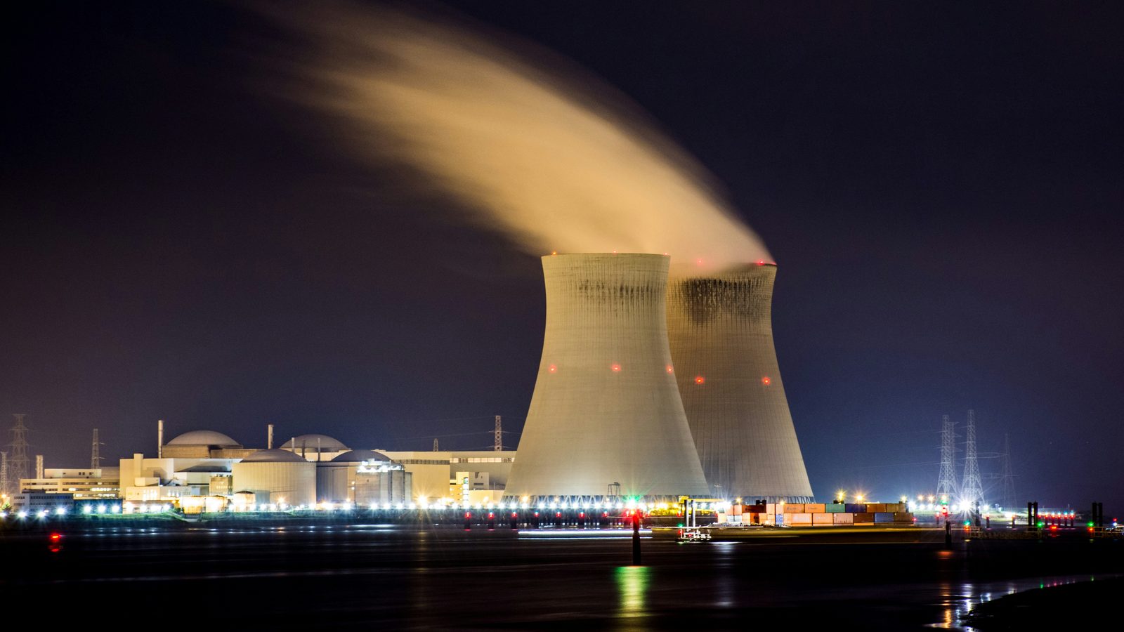 Nuclear plant control room, instrument panels, operators in plant uniform.
